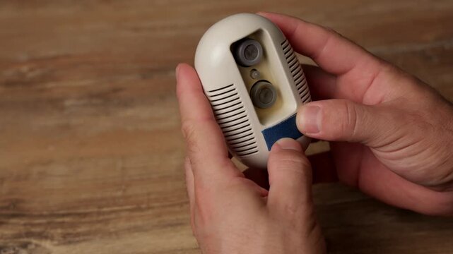 Hands check an operating gas and smoke leak detector for safety and functionality
