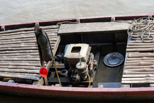 Close-up of a small diesel engine installed inside a wooden boat. Motorized water transport machinery setup on a river boat deck.