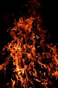 Burning embers beneath bright fire. Embers glowing beneath bonfire flames. Glowing embers with blazing fire. Embers burning beneath flames in motion.