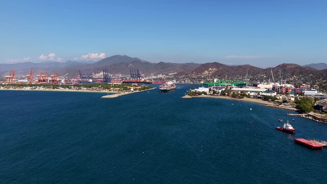 High angle aerial shot of a large cargo vessel navigating the harbor entrance at the Port of Manzanillo, showcasing global trade and maritime logistics.