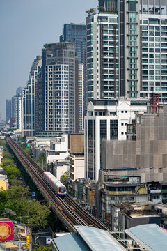 BTS Skytrain crosses elevated tracks between modern towers and older city blocks in central Bangkok, showing contrasting urban architecture, Thailand, Bangkok, April 26, 2026.