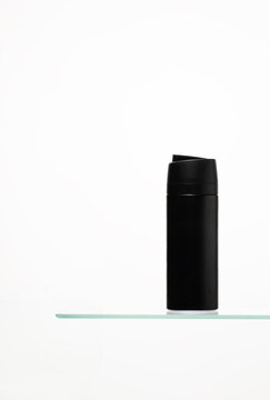 Abstract shaving product in black color on glass shelf. Ideal for advertising skin care, hygiene, and luxury grooming brands.