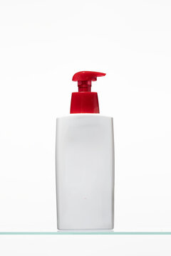 A clean, minimalist studio shot of a white plastic dispenser bottle with a vibrant red pump head. Set against a pure white background, this product photo is ideal for skincare or hygiene branding.
