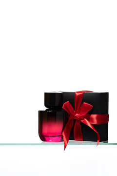 Minimalist beauty gift set featuring perfume bottle, and black present box with red bow for e-commerce product listings, Black Friday beauty deals, and luxury spa gift vouchers.