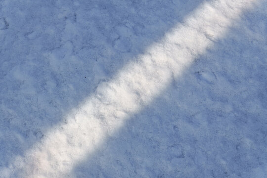 A Diagonal Band of Sunlight Crosses Snowy Ground
