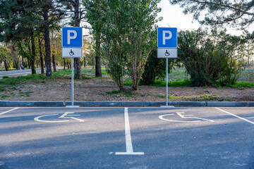 Disabled parking spaces with signs and wheelchair road markings in a park area. Two empty parking bays dedicated for people with disabilities. © Dina Luk