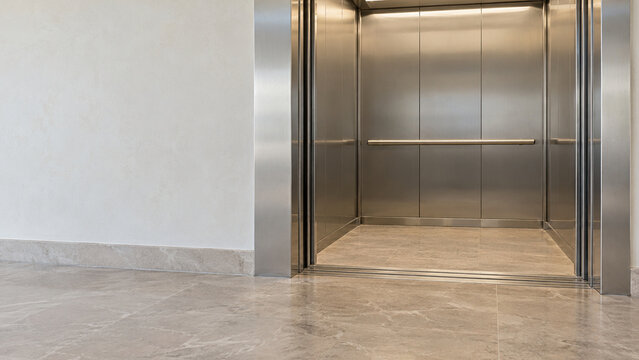 Open elevator with level floor threshold and metal handrail