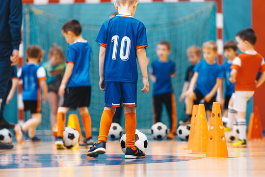 Group of young boys practicing indoor soccer during a training session in a school gymnasium. Youth futsal player skills action shot inside a sports hall.