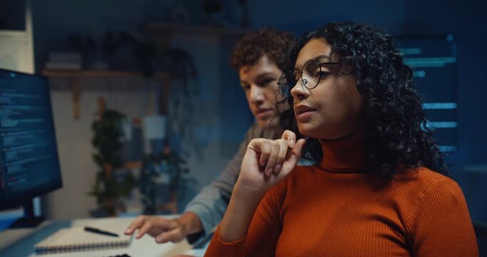 Diverse team software developer discuss AI coding project strategy in dark office at night. Creative startup group brainstorming, Mentor code review training, Digital communication innovation concept.
