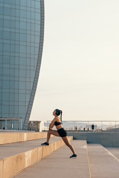 A woman stretches on a concrete step in the city before her workout