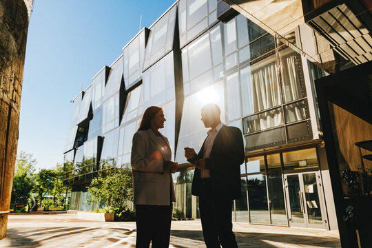 Business colleagues talking outdoors by modern office building