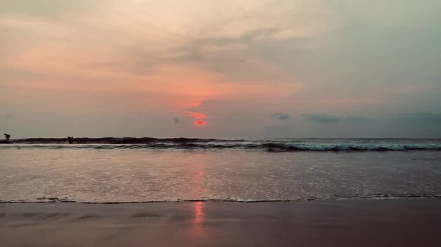 HD video of real-time sunset at  kuta beach bali,  Indonesia featuring gentle ocean waves rolling onto the sandy shore during dusk.