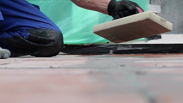 Worker kneeling while lifting tile during floor installation project