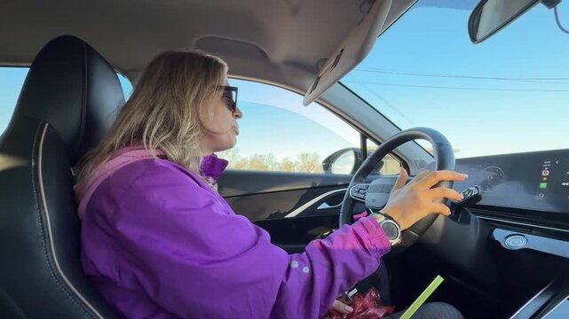 Woman driving car, female motorist navigating highway road. Static interior side view shot.