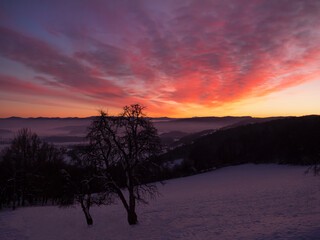 Naklejka premium Stunning vista of vibrant atmospheric mood above snowy hilly rural landscape