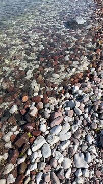 Sea surf on a rocky Baltic beach. Green seaweed sways on the gentle waves. Estonia, Hiiumaa.