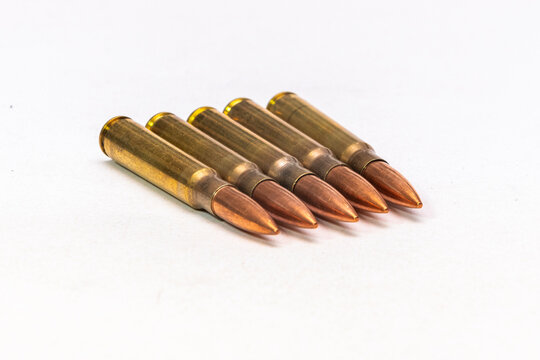 Five rifle cartridges arranged neatly on a white isolated background