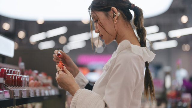 Gen z woman shopping for cosmetics in a modern beauty store choosing makeup trend products on a shelf