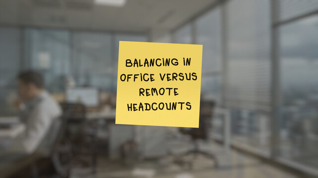 Memo with the text "balancing in office versus remote headcounts" in the front, superimposed on a blurred background showing an collaborative workspace.