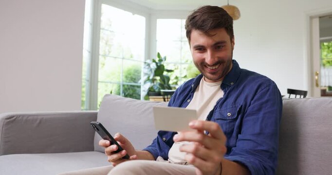 Smiling man reading a blank card while holding a smartphone