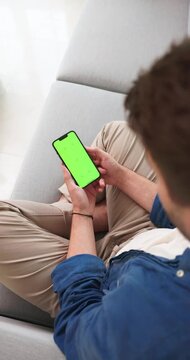 Smartphone held sideways with a green screen on a sofa