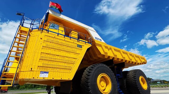Belarus, Minsk 18.06.2026: A massive yellow BelAZ haul truck set against a blue sky with white clouds; heavy industrial machinery used for transporting heavy loads in open-pit mines