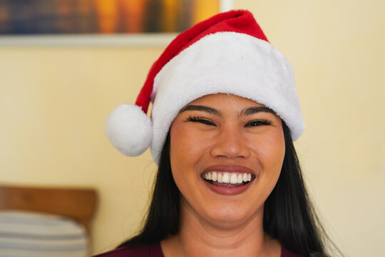 Happy young asian girl wearing santa claus hat during christmas time and smiling on camera - Winter season, holiday and festive concept - UGC content