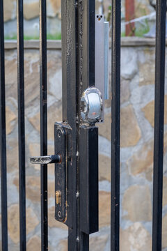 An electronic access control lock system with an RFID reader and magnetic lock is installed on a black metal gate.