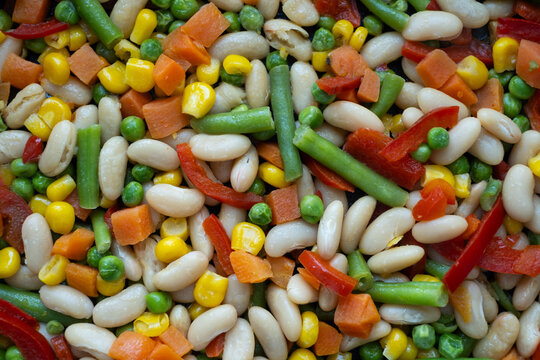Mixed vegetables with white beans, corn, green peas, carrot and red pepper, colorful frozen vegetable mix food background, full frame