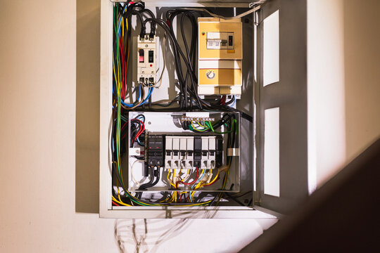 Open electrical board and circuit breaker box installed on a wall.