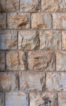 Warm sunlit chiseled limestone wall background with relief block pattern