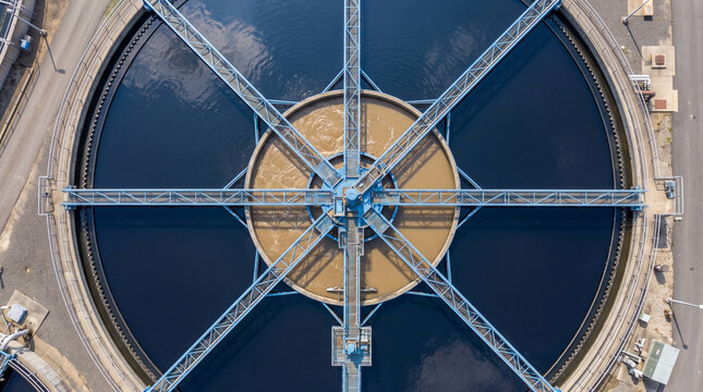 Aerial view of a circular wastewater treatment plant clarifier tank with rotating mechanical arms