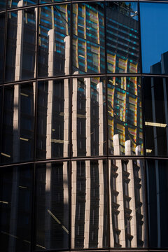 Distorted reflections of tall buildings across a dark glass facade in London create layered vertical patterns and a graphic study of modern architecture