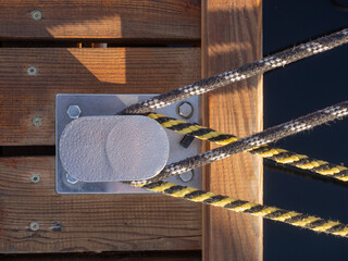 Mooring Ropes Secured to Metal Cleat on Wooden Dock at Marina, Closeup Nautical Detail © Michał Kiełbicki