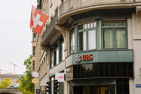 Zurich, Switzerland, October 7, 2026. The UBS bank branch facade with Swiss flag waving on Bahnhofstrasse building.