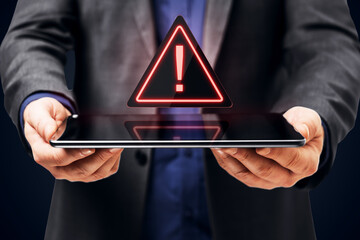 Fototapeta premium Businessperson Holding a Tablet with Glowing Exclamation Warning Symbol for Digital Security, Online Alert, Mobile Technology and Risk Awareness.