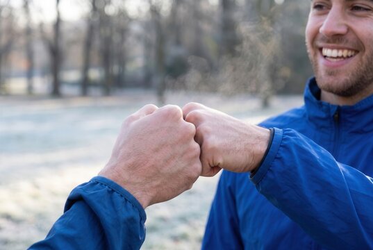 Two men sharing a friendly fist bump outdoors in winter, showing teamwork and greeting