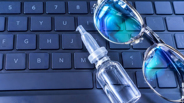 Blue Computer Keyboard with Reading Glasses and Eyedropper for Digital Eye Strain Concept