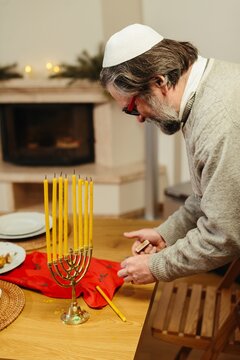 Jewish man preparing menorah for hanukkah celebration