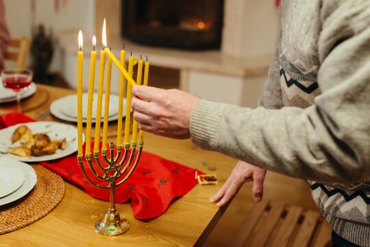 Person lighting hanukkah menorah candles at home