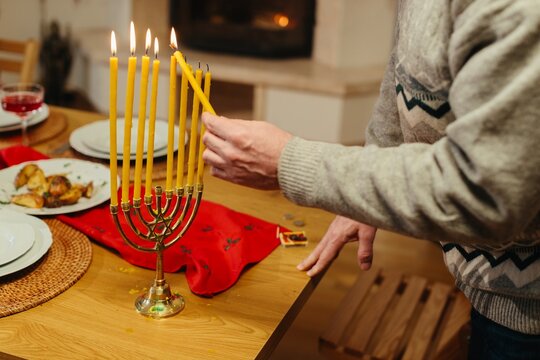 Man lighting candles on hanukkah menorah during celebration