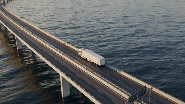 The camera rises from an elevated three-quarter view of a white semi truck to a wide coastal panorama showing the bridge, offshore wind farm and distant city skyline.