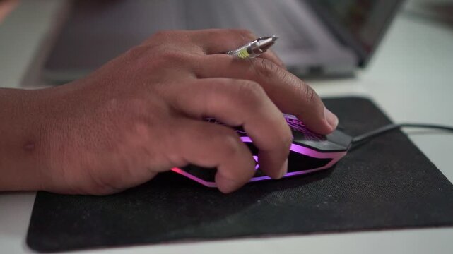 Hand gripping a technical pen over a black mouse pad on a desk. Engineering, drafting and precision drawing tool background.