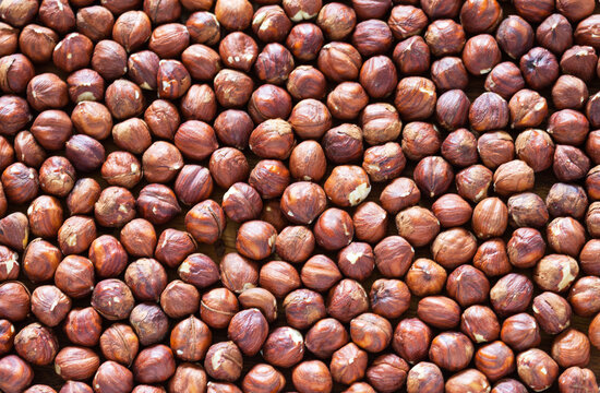 Edible background of shelled brown hazelnuts. Organic, healthy vegetarian food. Close-up, top view, flat lay, creative design layout