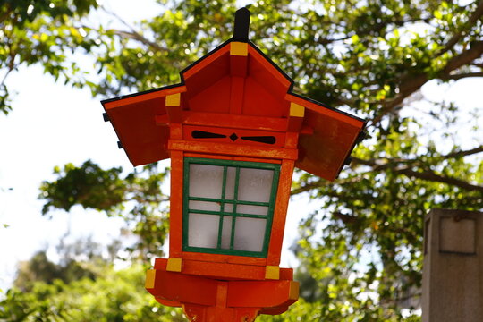 A close-up of a vermilion wooden lantern at a Japanese shrine.