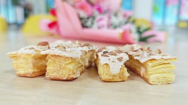 Four French Jesuite puff pastries aligned in a row on a light wooden table.