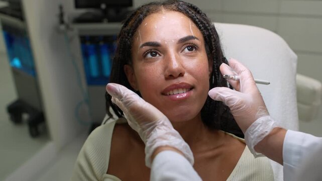 Cosmetology consultation with cheekbone palpation for an African woman. 4k video of midface anatomy assessment and facial contour planning before aesthetic treatmen