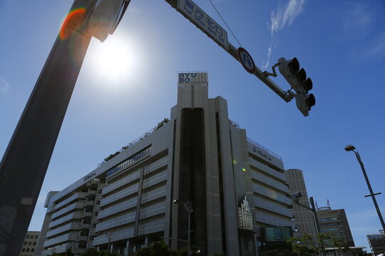 A low angle view of a department store building under bright sunlight in Okinawa.