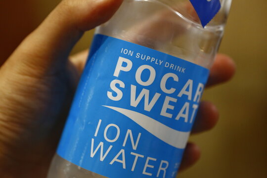 A close-up of a person holding an ion water sports drink bottle.