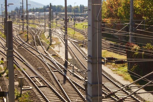 Complex railway junction with multiple intersecting train tracks, switches and overhead electric power lines. 
